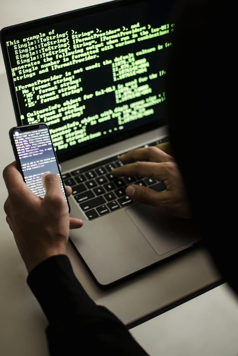 an individual operating a laptop and cellular device simultaneously